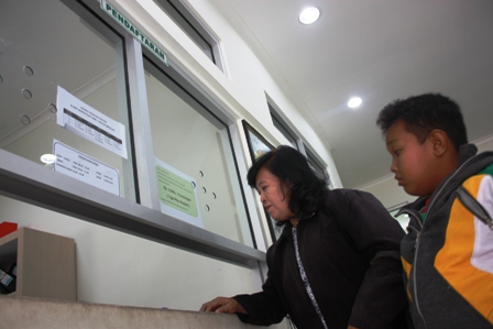 Seorang ibu bersama anaknya yang sakit sedang mendaftar di klinik